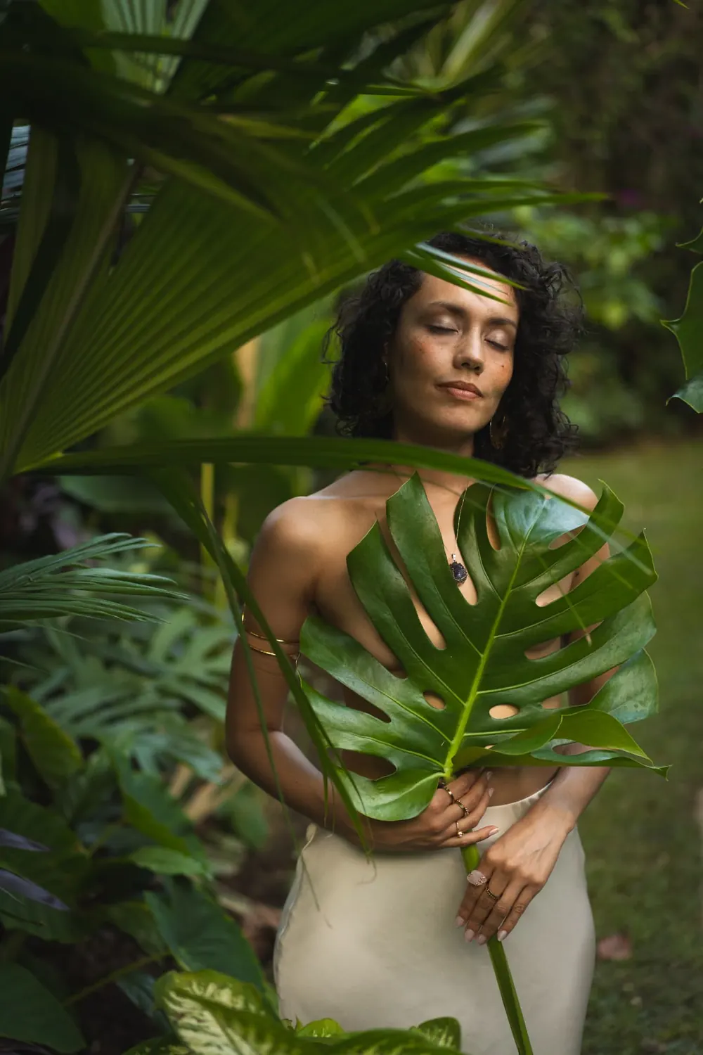 Sara Chalarca con los ojos cerrados entre hojas tropicales